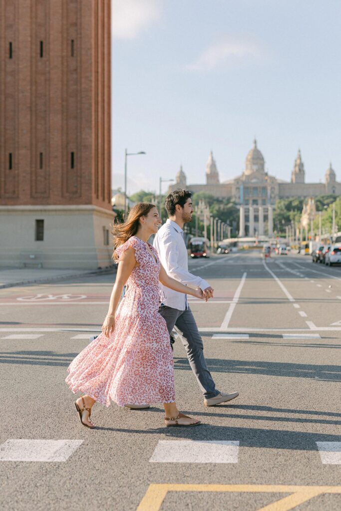 Young couple crossing the street of barcelona after the surprise marriage proposal on the top of MNAC museum in Barcelona