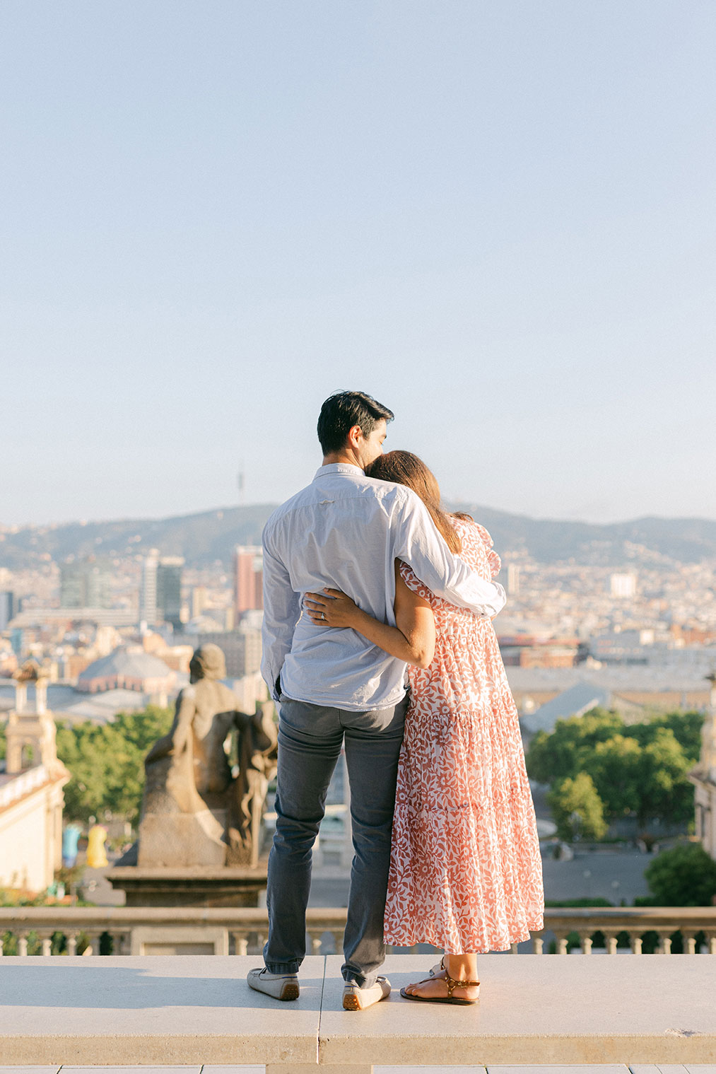 Young couple hugging after the surprise marriage proposal on the top of MNAC museum in Barcelona